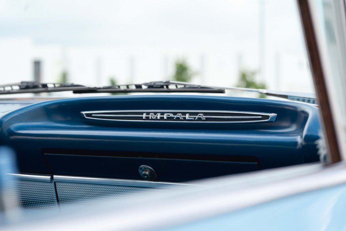 Close-up of a blue 1963 Chevrolet Impala's dashboard with "IMPALA" chrome trim.