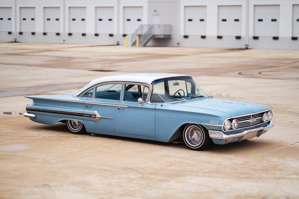 1960 Chevrolet Impala lowrider, light blue with white roof, custom chrome rims, lowered suspension.