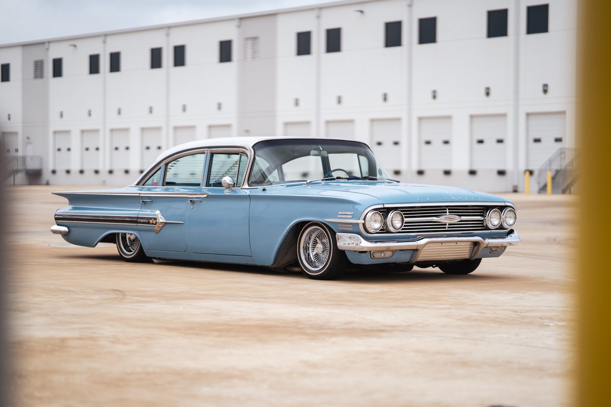 1960 blue Chevrolet Impala lowrider with chrome rims and whitewall tires.