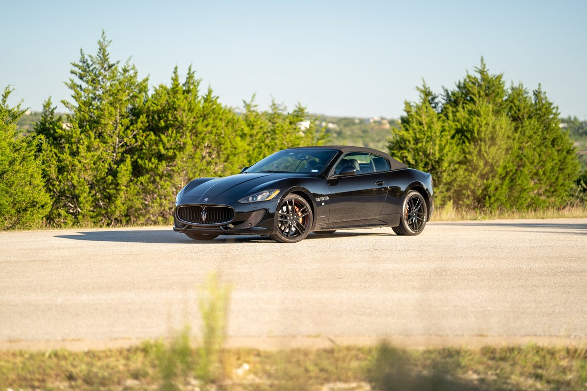 Black 2016 Maserati GranTurismo convertible with black rims on a road.