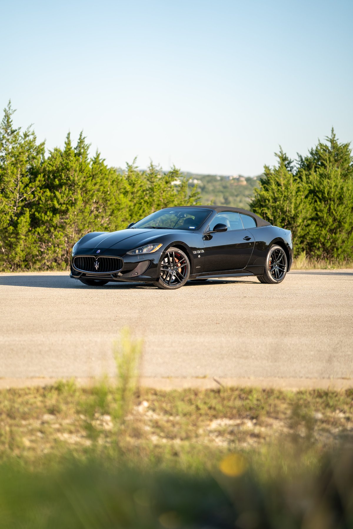 Black 2016 Maserati GranTurismo convertible with red brake calipers and alloy rims.