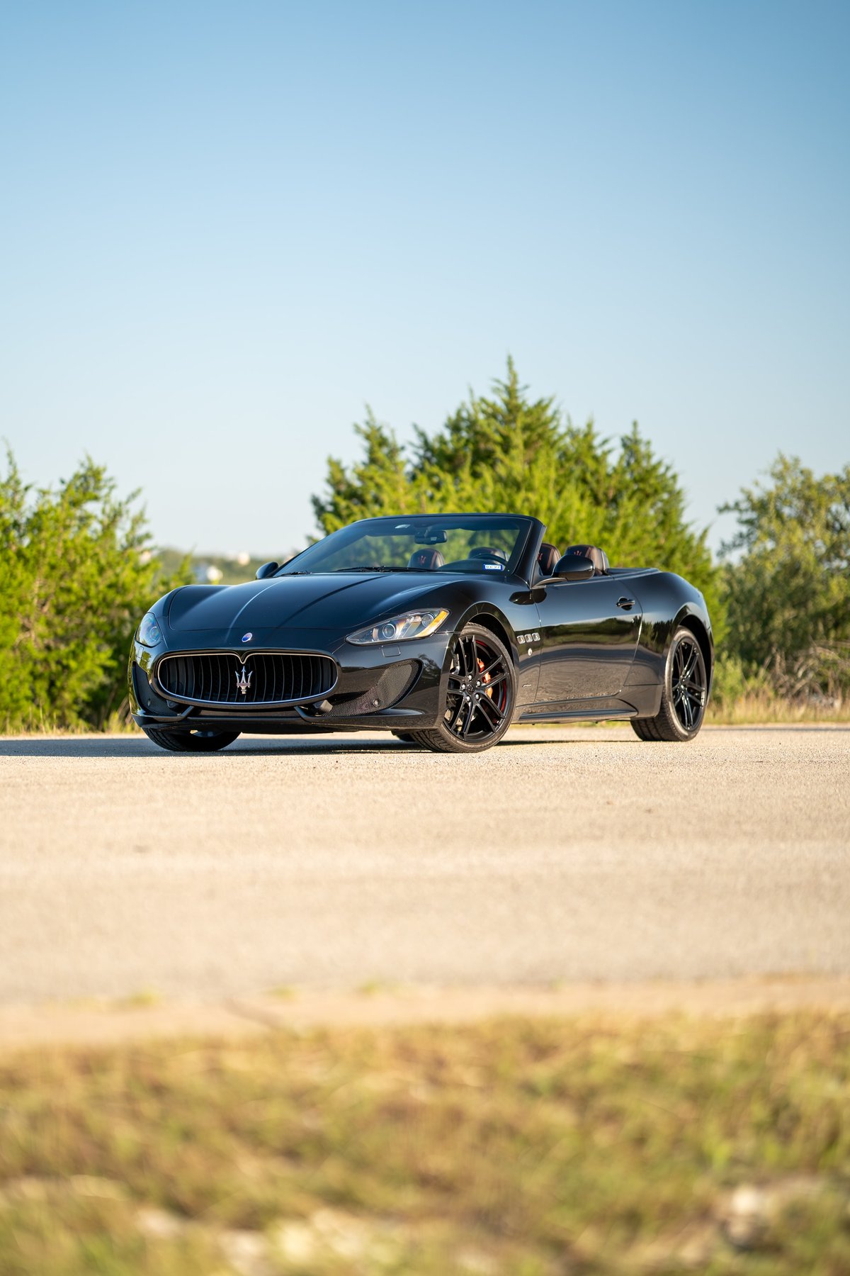 Black 2016 Maserati GranTurismo convertible with black rims and red brake calipers.