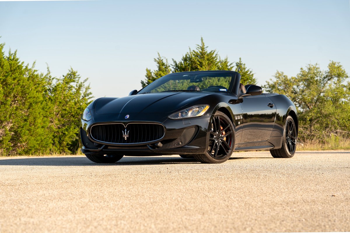 Black 2016 Maserati GranTurismo convertible with black rims and red brake calipers.