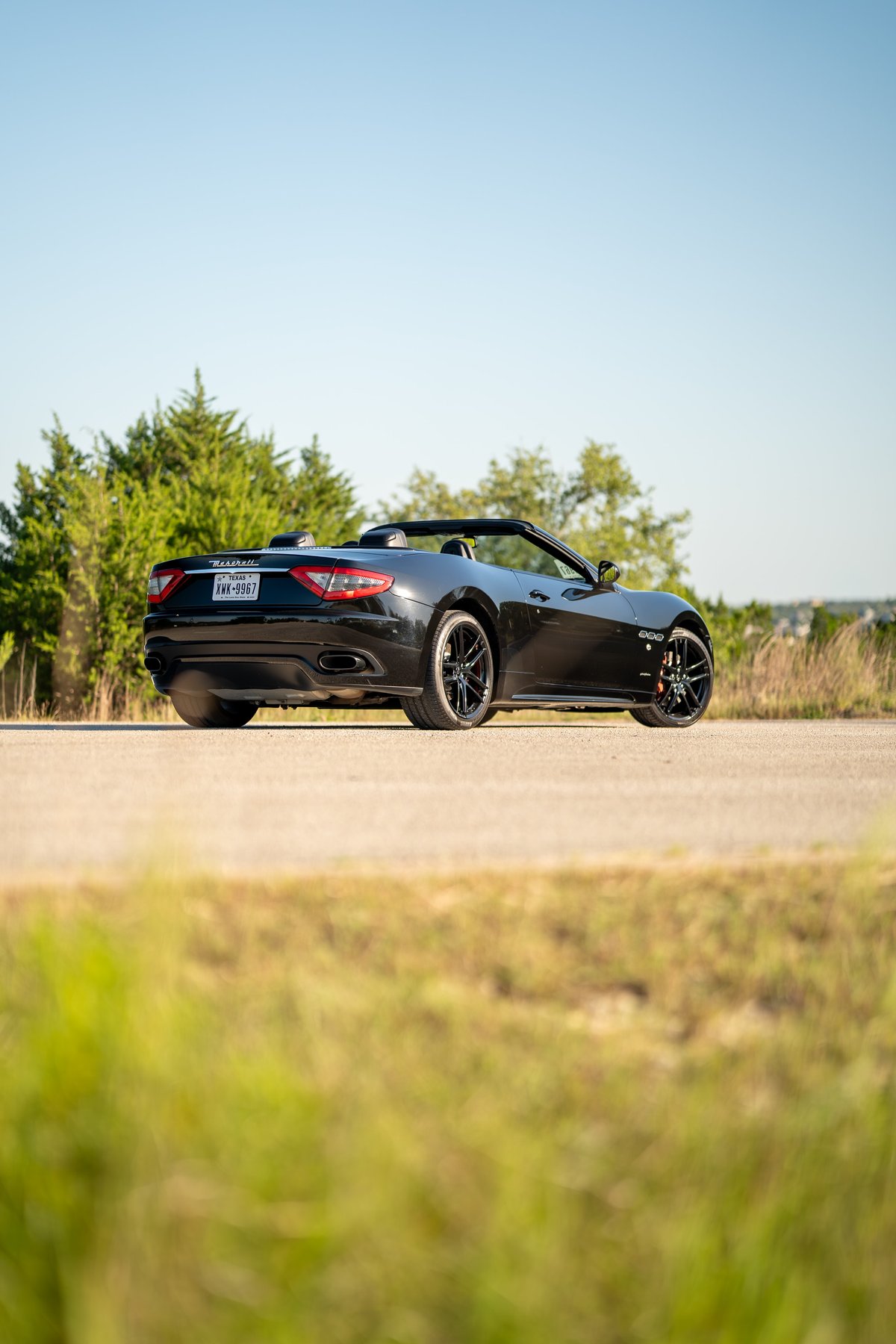 Black 2016 Maserati GranTurismo convertible with black rims and red brake calipers.