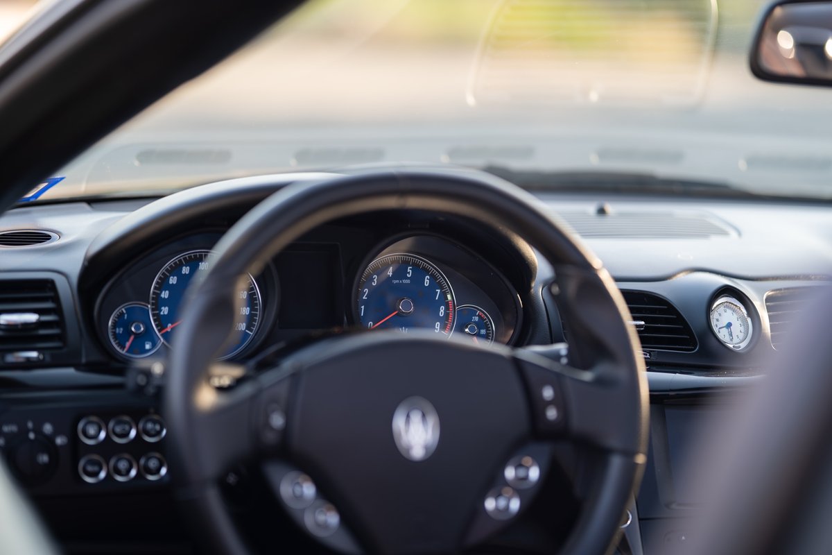 Maserati GranTurismo dashboard with analog clock and blue-dialed gauges.