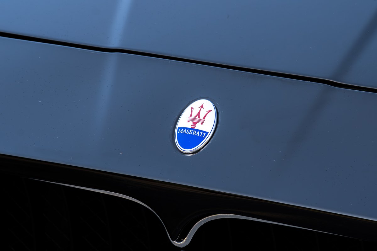 Close-up of a Maserati GranTurismo's badge on its black hood.