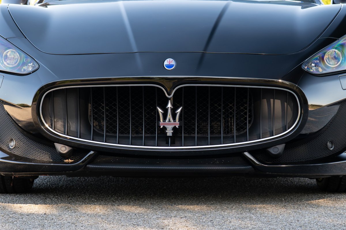 Front view of a black 2016 Maserati GranTurismo showing its iconic trident grille and carbon fiber trim.
