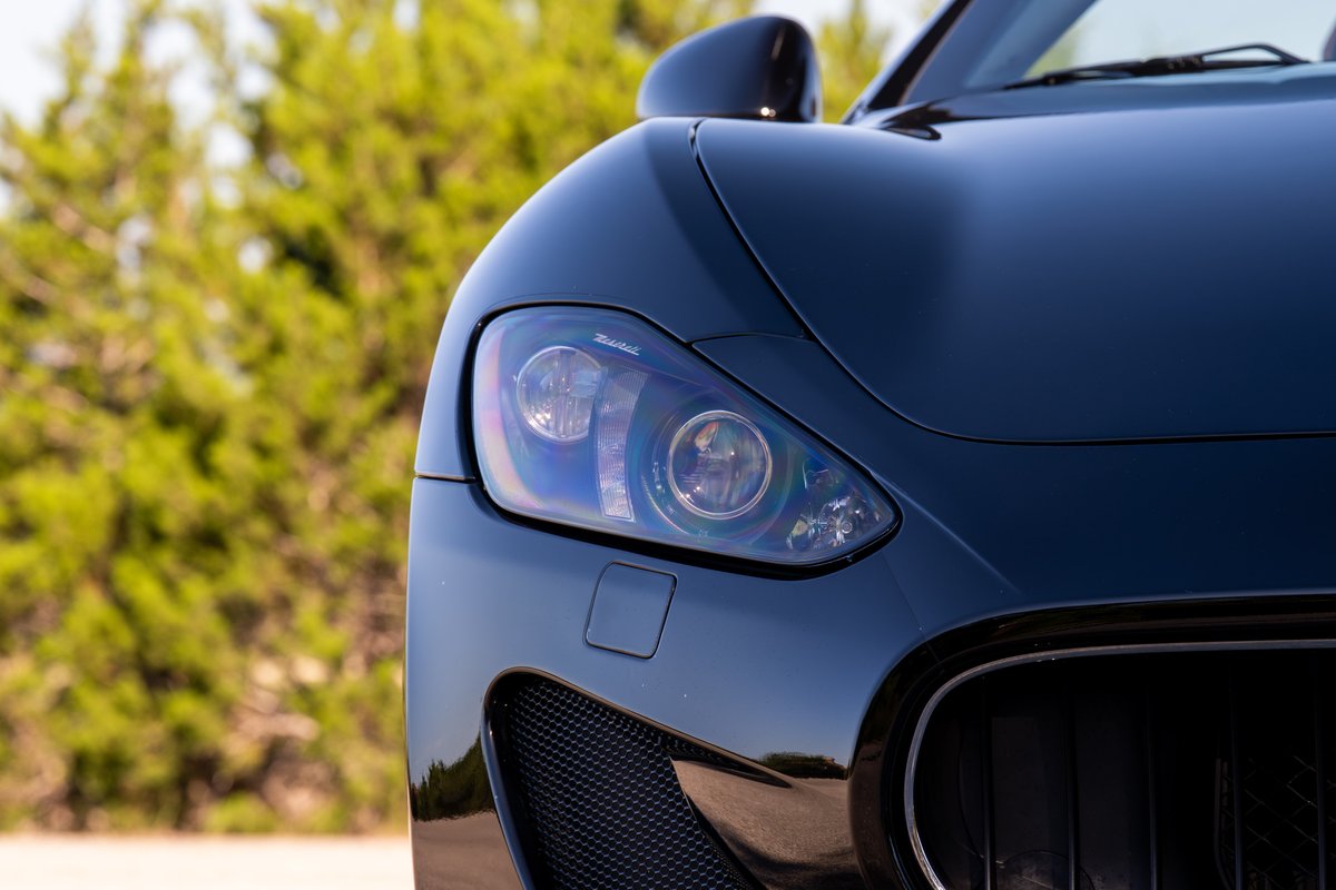 Close-up of a black 2016 Maserati GranTurismo, focusing on the headlight and grille detail.
