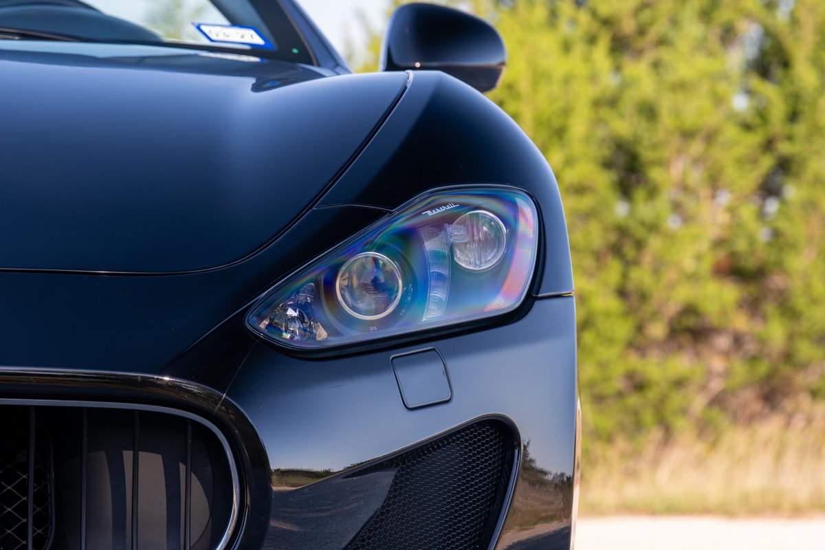 Close-up of a black 2016 Maserati GranTurismo headlight and grille.