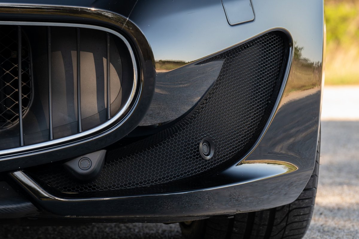 Front bumper detail of a black 2016 Maserati GranTurismo with parking sensors.