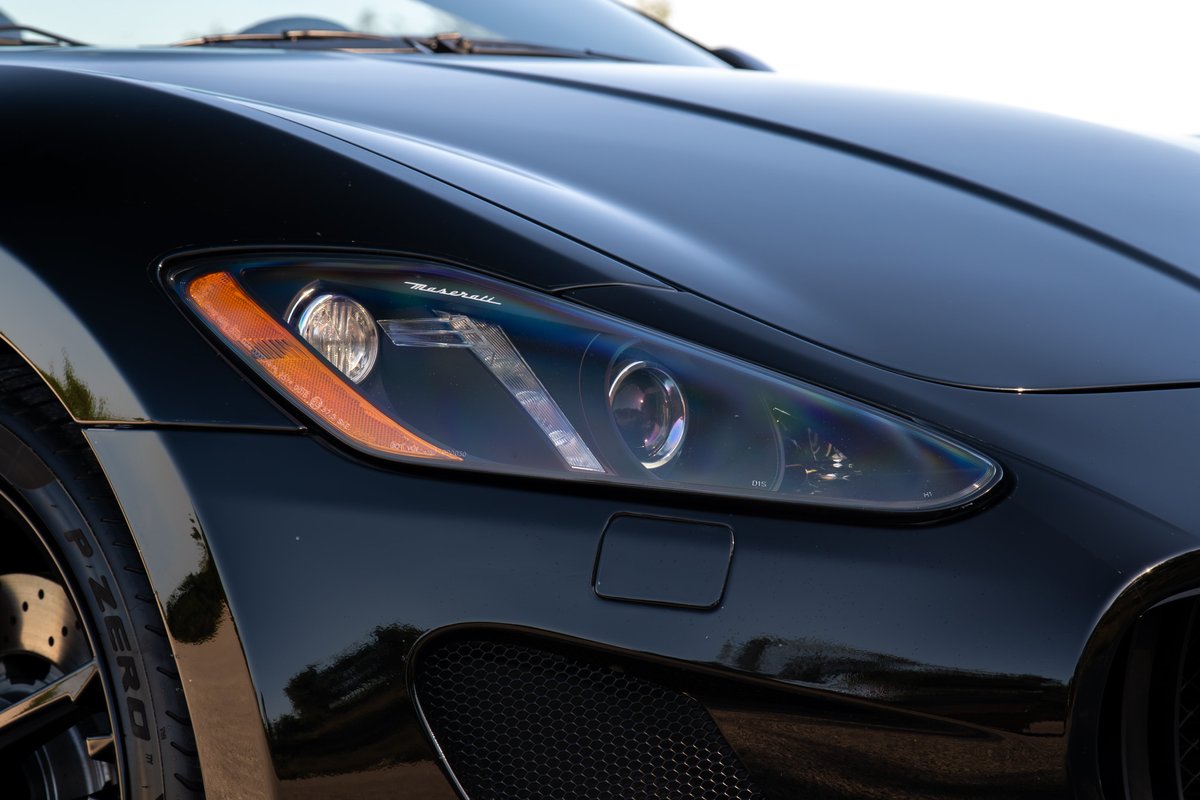 Close-up of a black 2016 Maserati GranTurismo headlight and front fender.