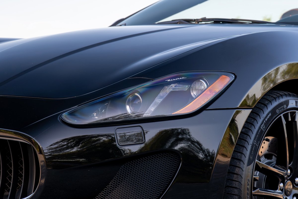 Black 2016 Maserati GranTurismo front fender, headlight, and black multi-spoke rims.