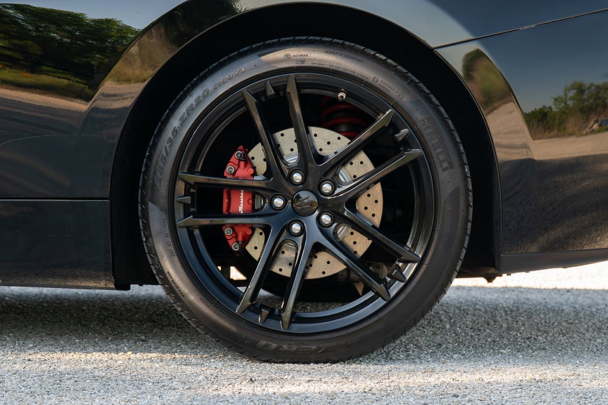 Black 2016 Maserati GranTurismo wheel with red brake calipers and perforated rotors.