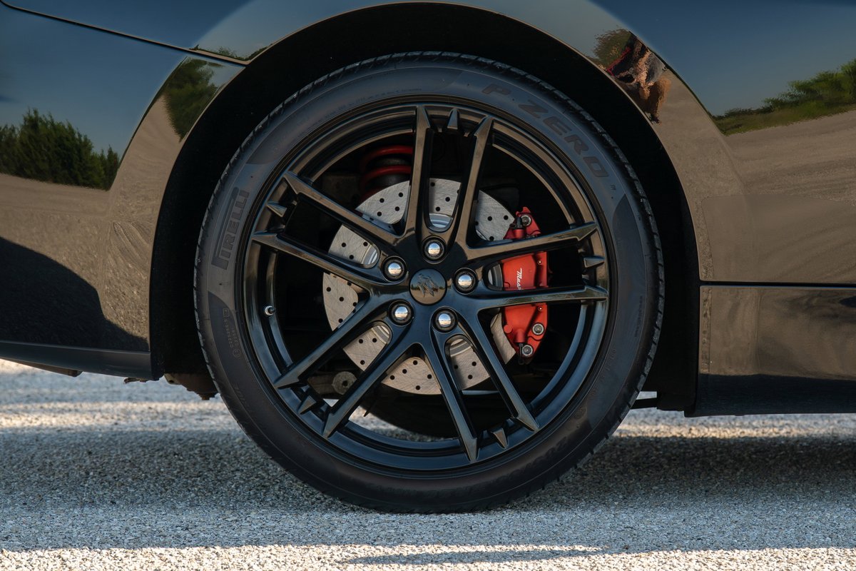 Black Maserati GranTurismo with black rims, red calipers, and drilled rotors.