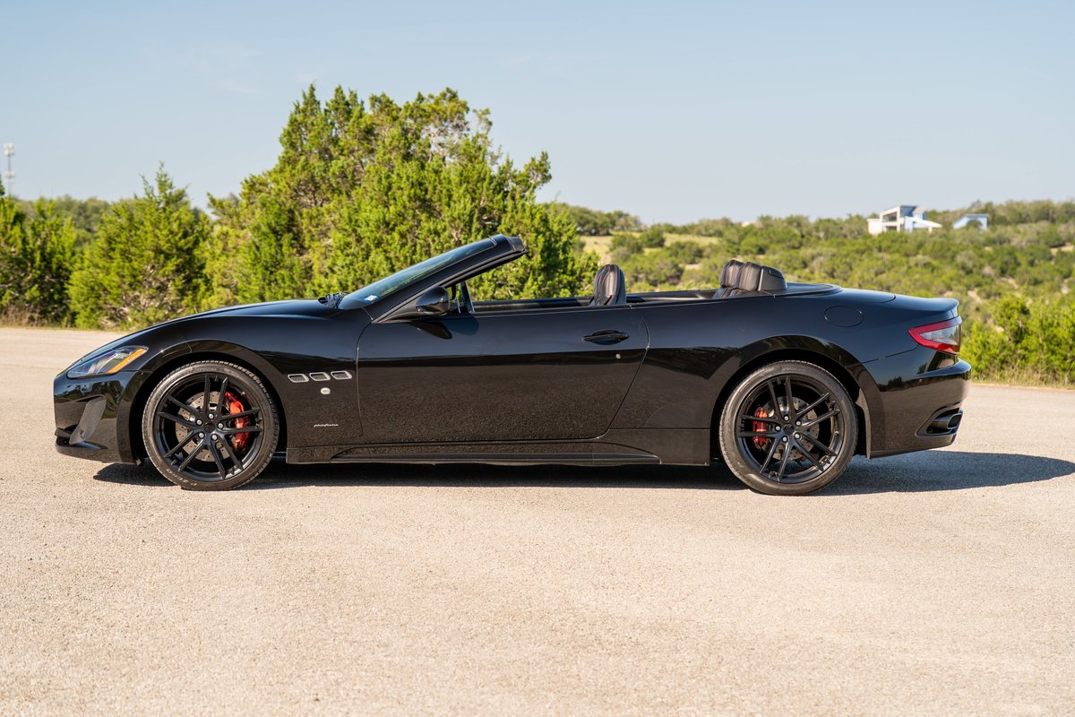 Black 2016 Maserati GranTurismo convertible with black rims and red brake calipers.