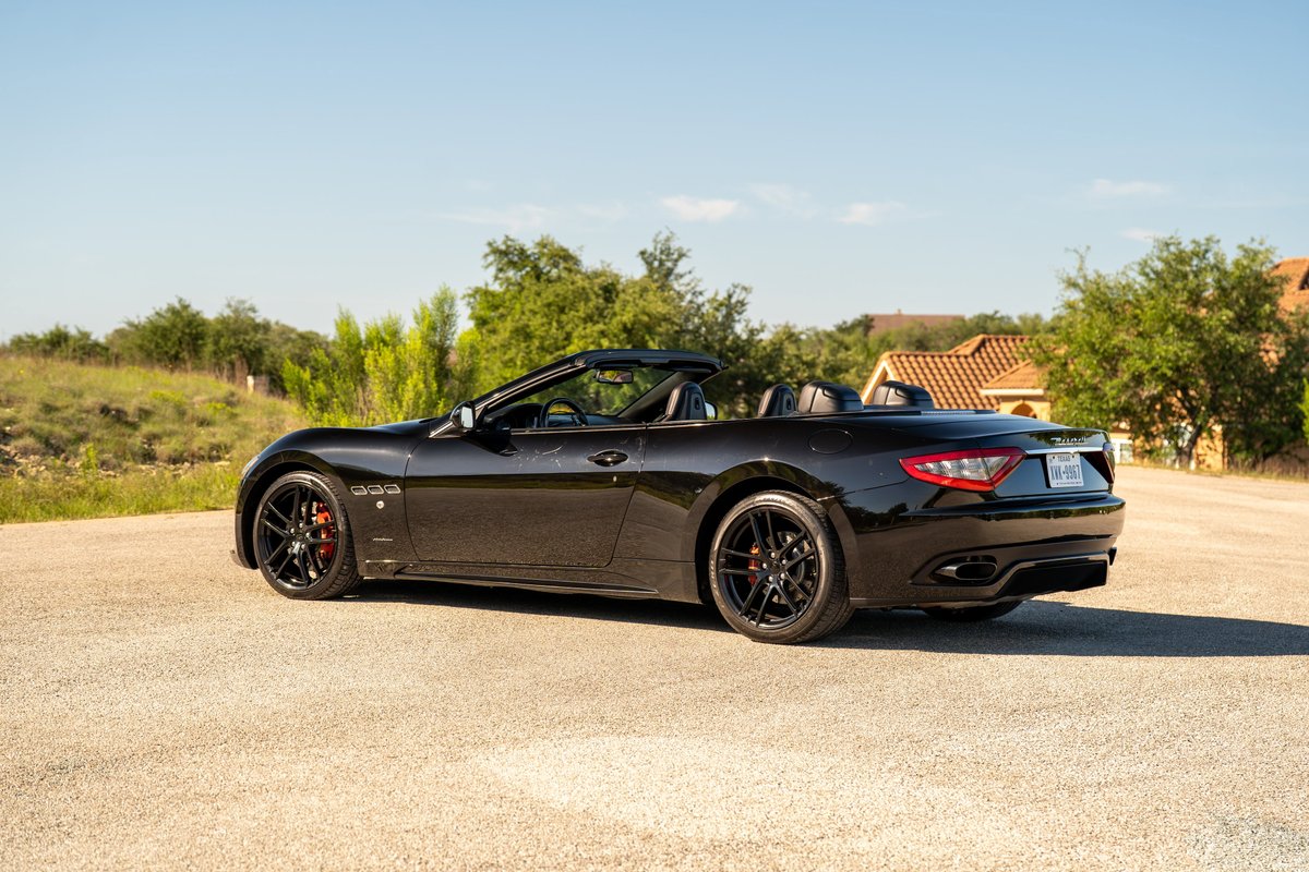 Black 2016 Maserati GranTurismo convertible with black rims and red brake calipers.