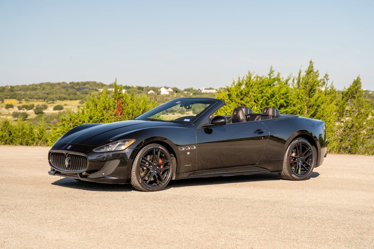 Black 2016 Maserati GranTurismo Convertible with black rims and red brake calipers.