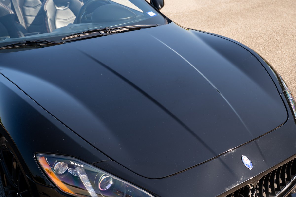 Close-up of a black 2016 Maserati GranTurismo hood and headlights.