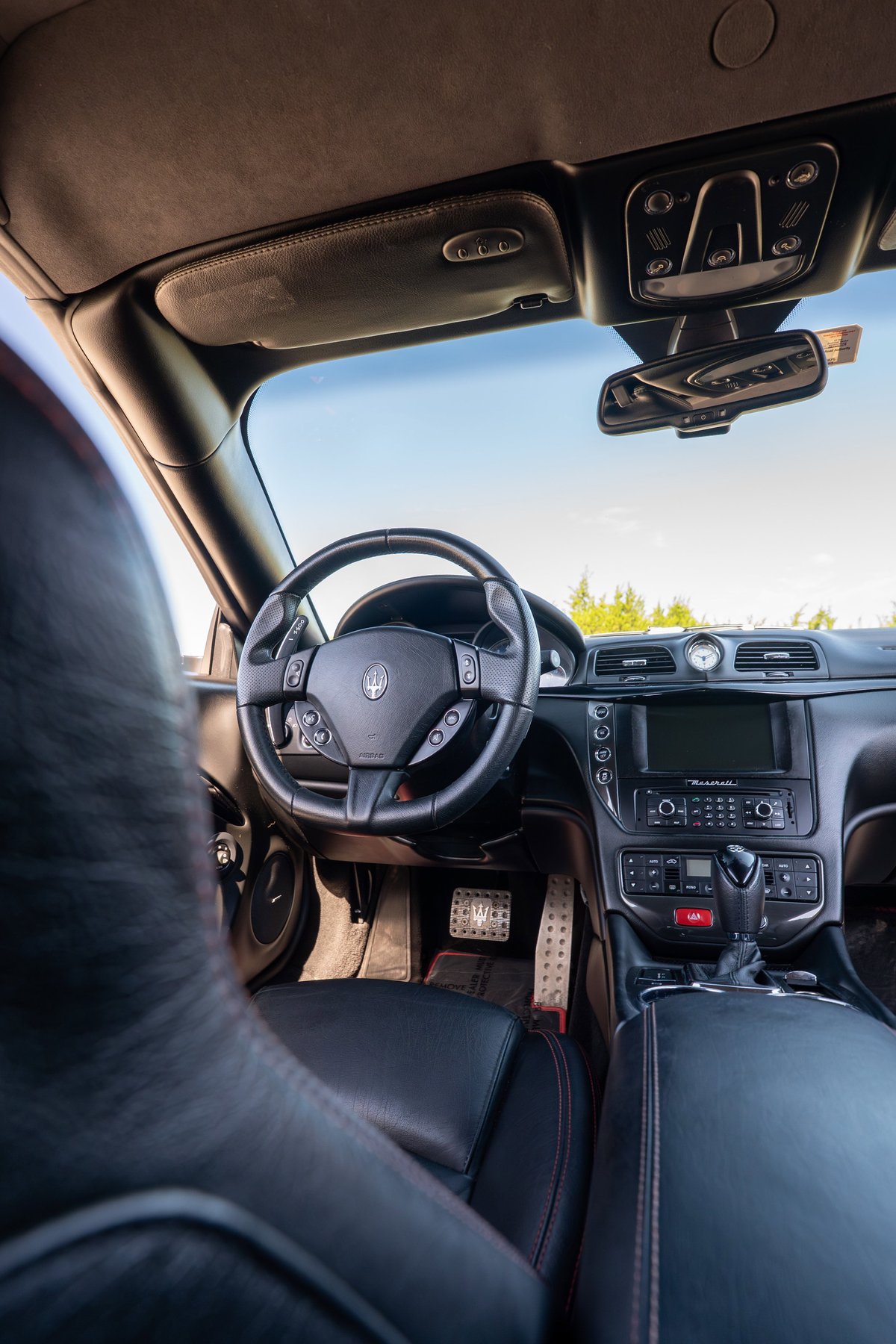 2016 Maserati GranTurismo interior with black leather, red stitching, and brushed metal pedals.