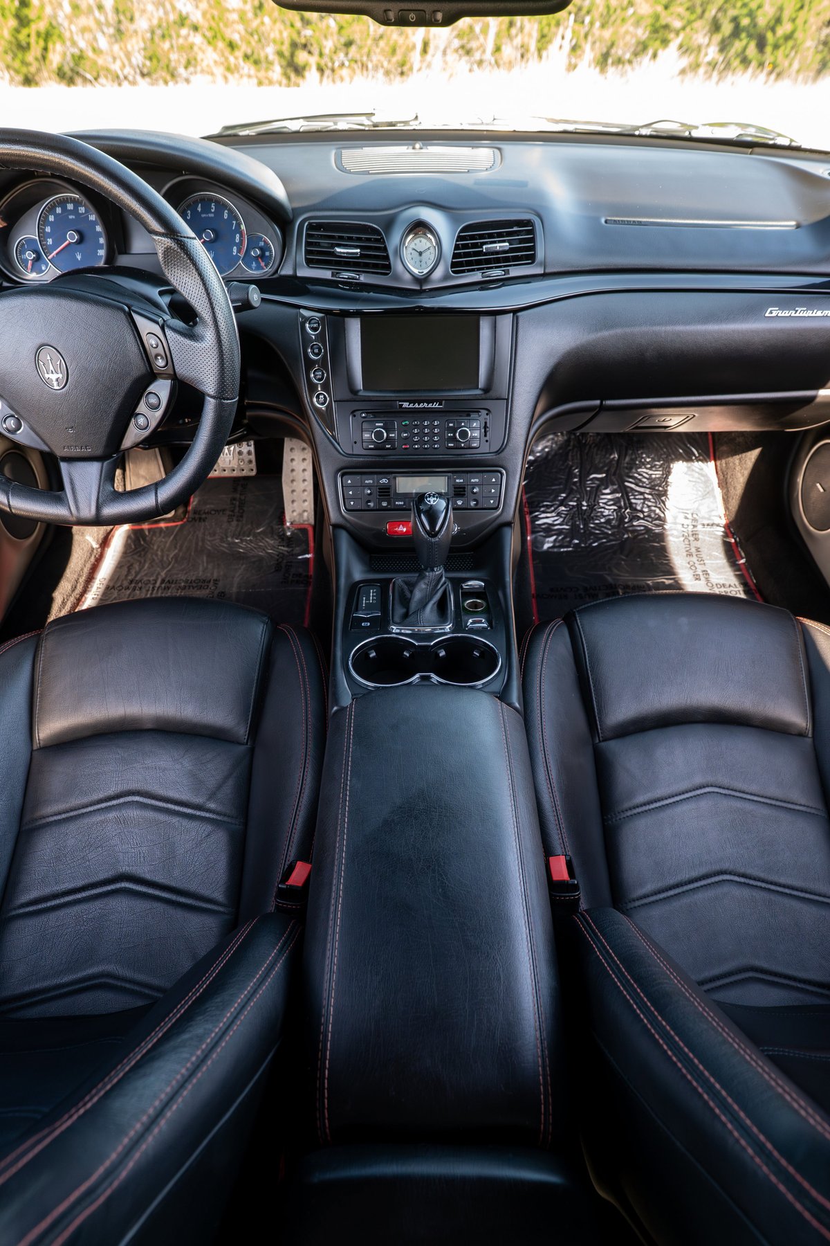 2016 Maserati GranTurismo interior with black leather seats, red stitching, and chrome trim.