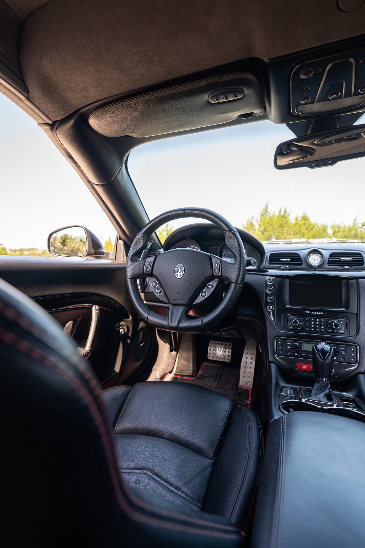Interior view of a black 2016 Maserati GranTurismo showcasing leather seats, steering wheel, and dashboard.