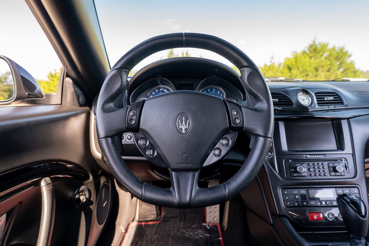 2016 Maserati GranTurismo interior shot. Black leather steering wheel with Trident logo.