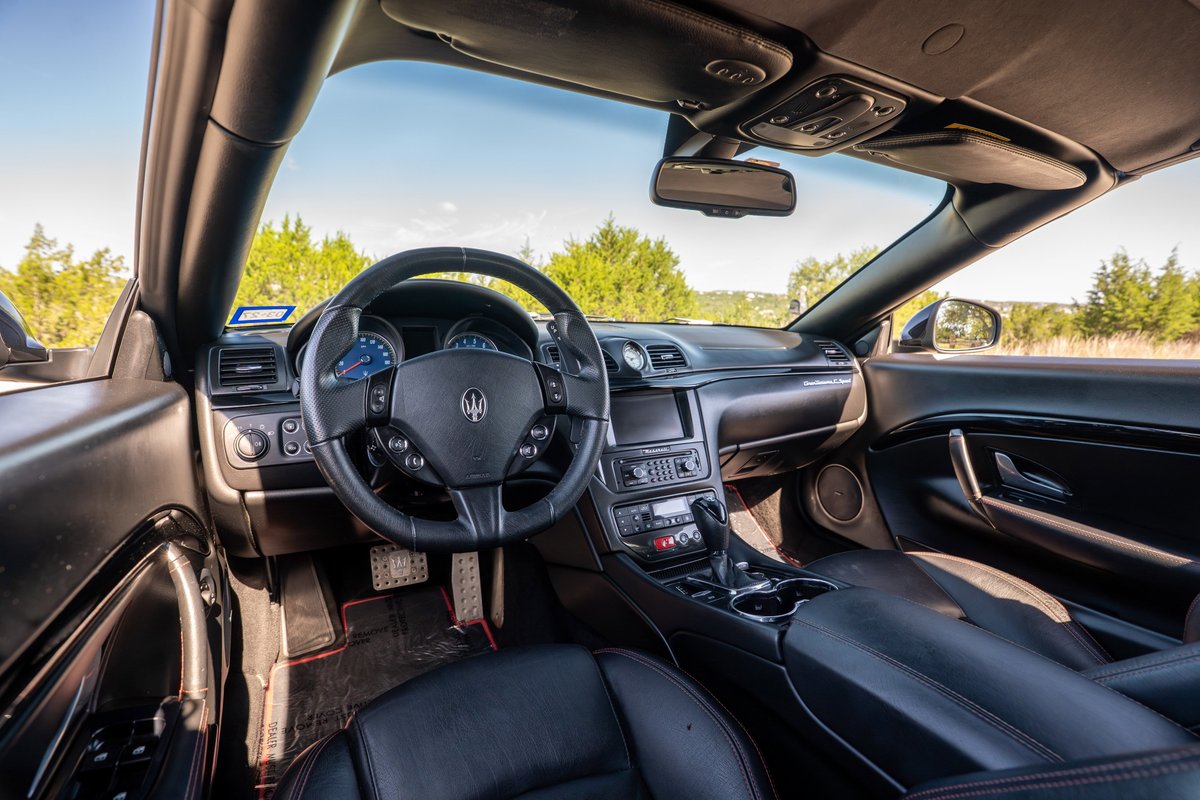 Interior view of a black 2016 Maserati GranTurismo convertible, showing dashboard and steering wheel.