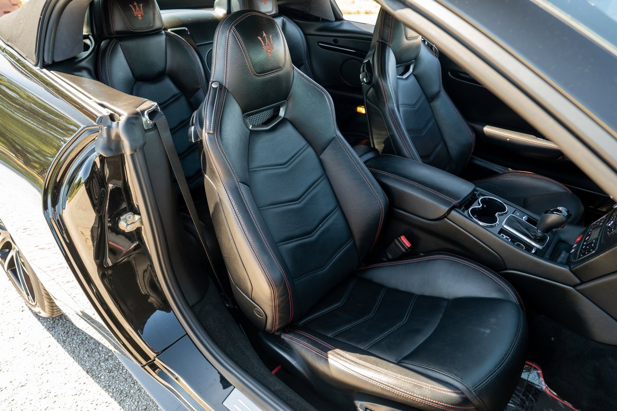 Black 2016 Maserati GranTurismo interior with quilted black leather sport seats and red stitching.
