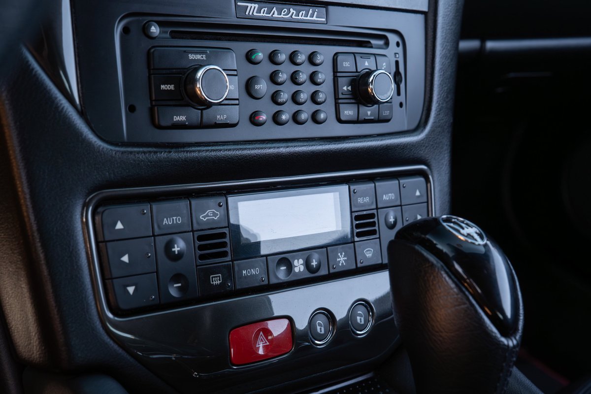 Maserati GranTurismo interior: close-up on the dashboard controls, shifter, and Maserati logo.