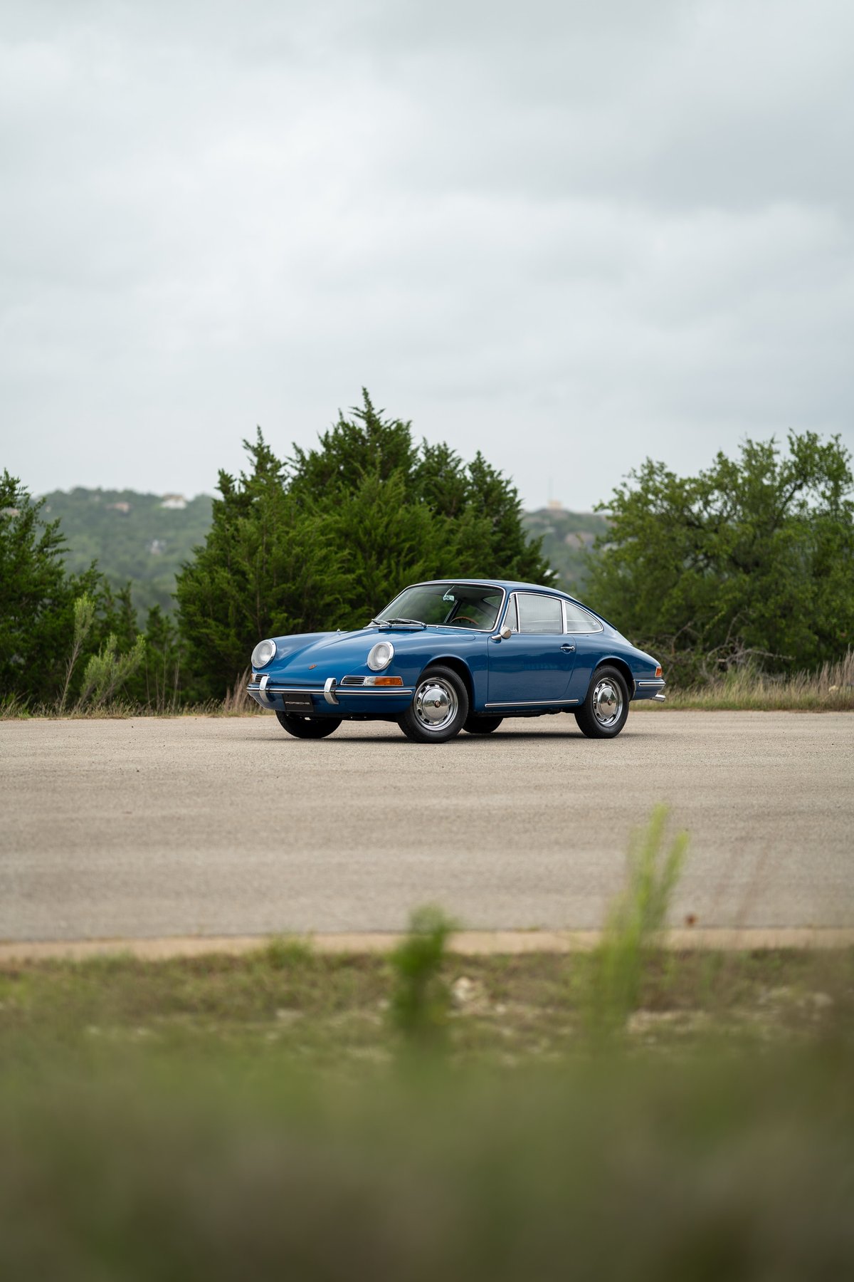 A vintage blue 1965 Porsche 912 coupe with chrome trim and classic rims.