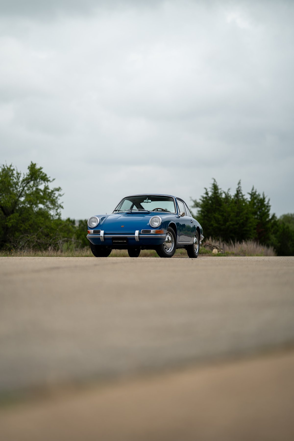 1965 blue Porsche 912 coupe with chrome rims and trim details parked on asphalt.