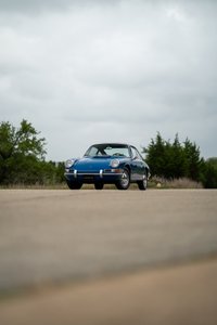 1965 blue Porsche 912 coupe with chrome rims and trim details parked on asphalt.