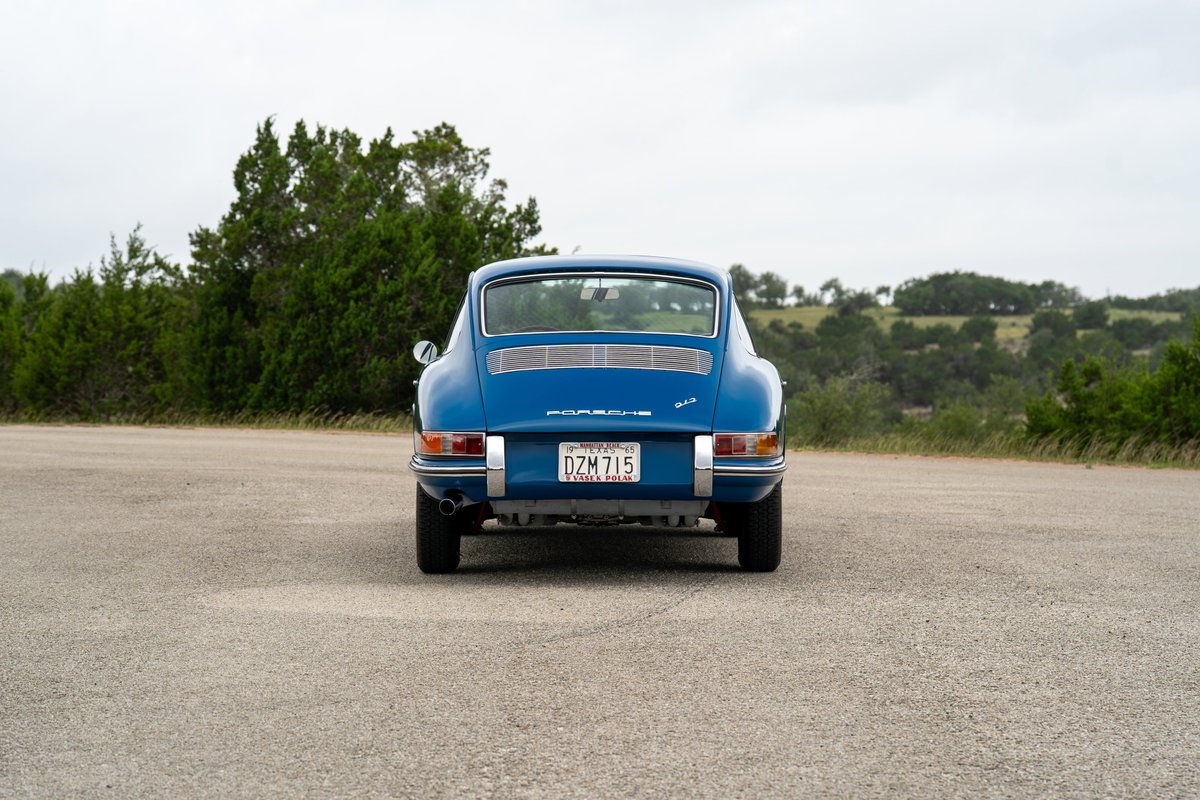 Rear view of a classic blue 1965 Porsche 912 coupe with chrome trim and a Texas license plate.