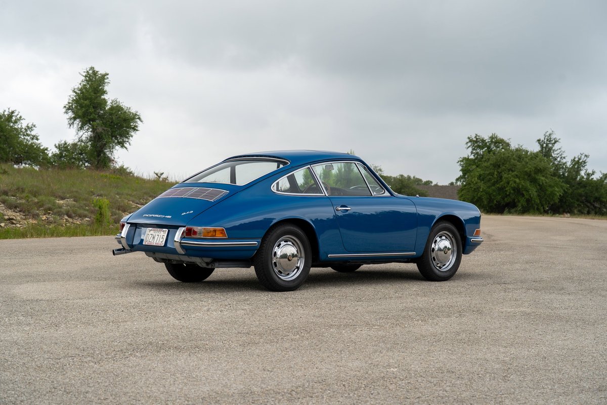 Rear 3/4 view of a blue 1965 Porsche 912 with chrome trim and wheels.