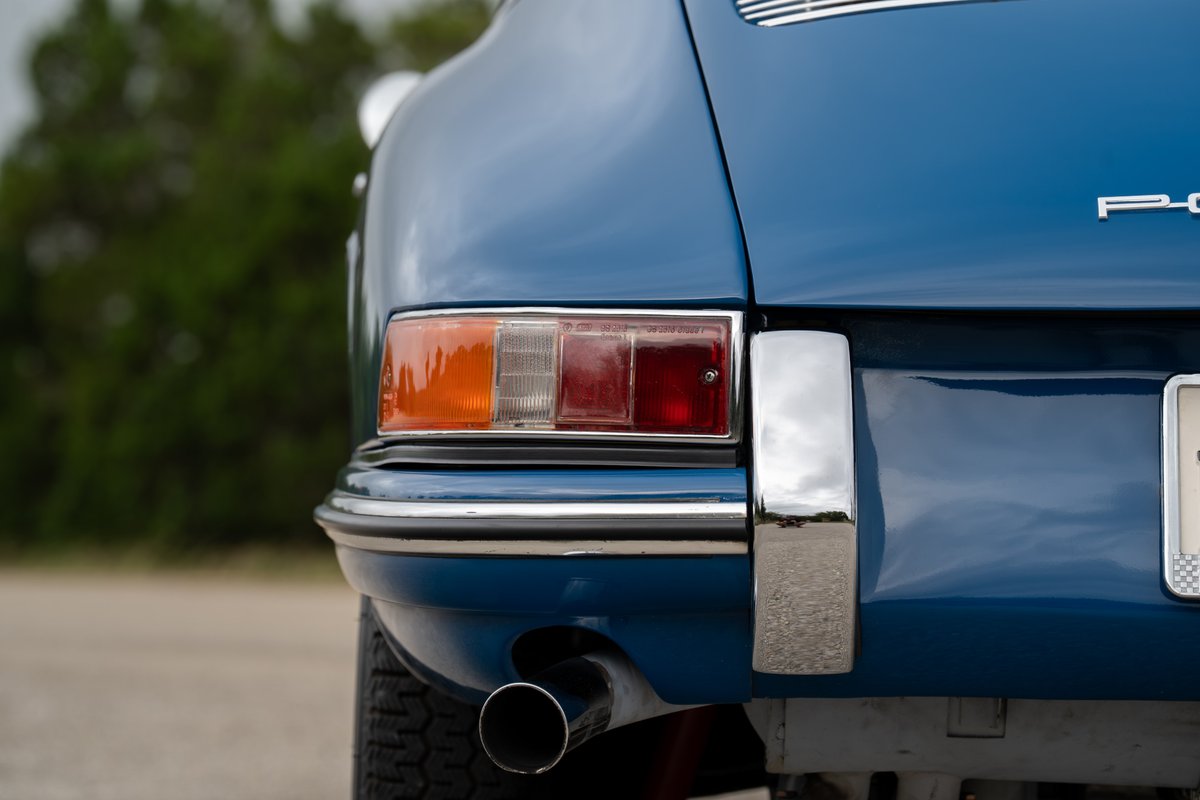 Close-up of a blue 1965 Porsche 912's rear bumper, taillight, and exhaust.
