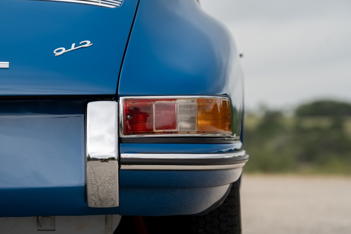Close-up of a blue 1965 Porsche 912's rear, showing the chrome bumper and taillight.