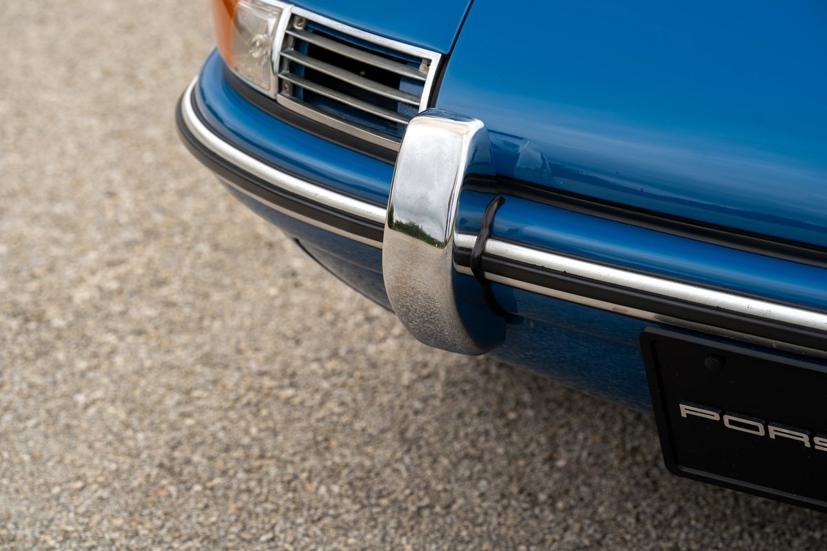 Close up of a classic blue Porsche 912 bumper and chrome trim.