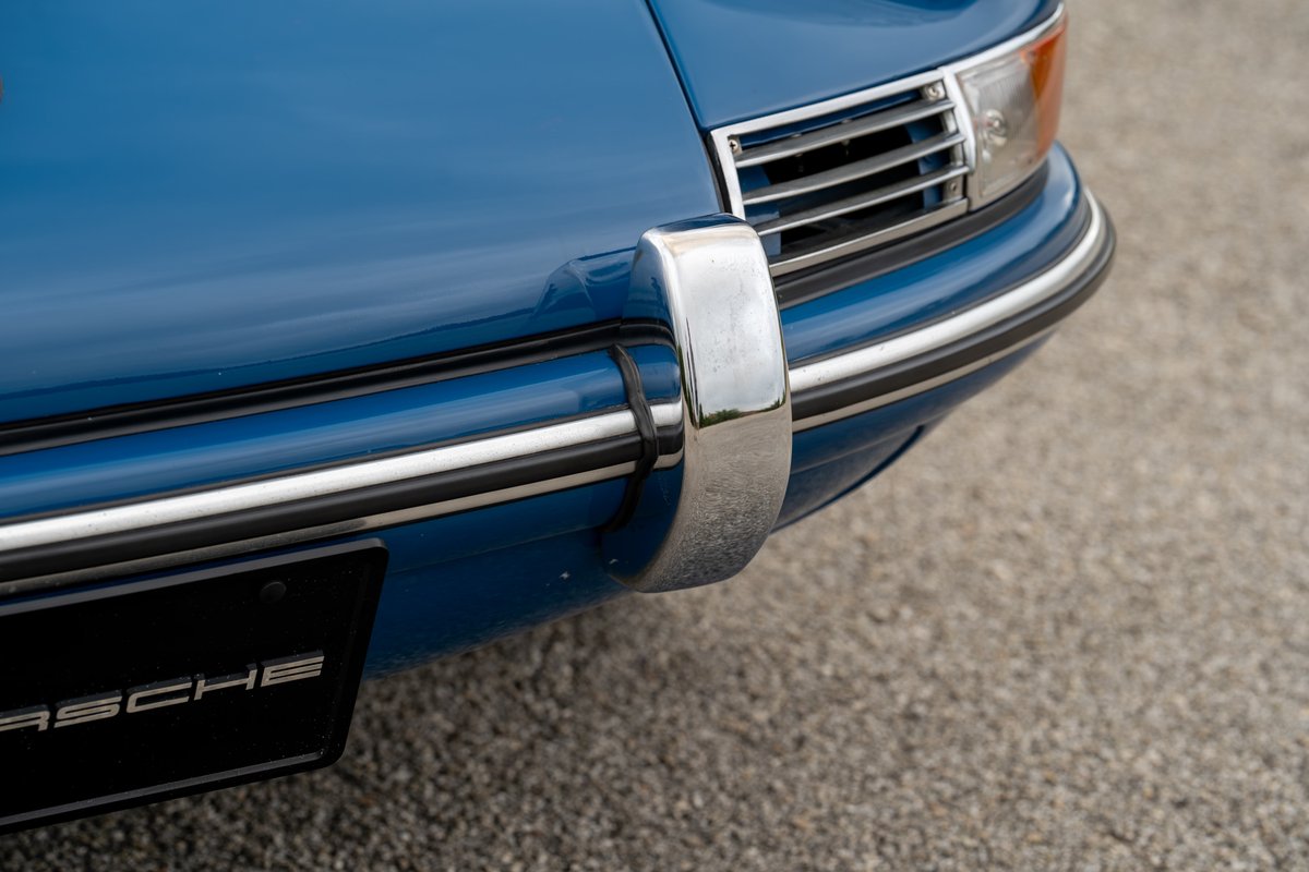 Close-up of a blue 1965 Porsche 912 front bumper with chrome trim and grille detail.