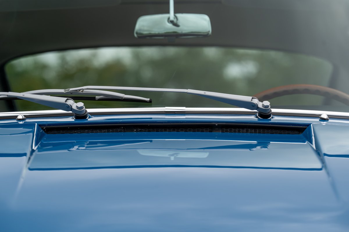 Close-up of vintage blue Porsche 912 hood, windshield wipers and interior mirror.