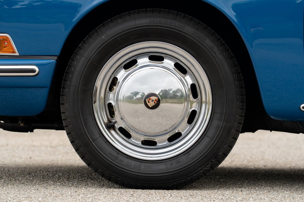 1965 blue Porsche 912 with chrome hubcaps on a classic rim.