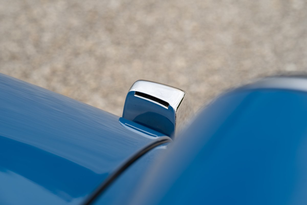 Close-up of a 1965 blue Porsche 912's chrome fuel filler trim.