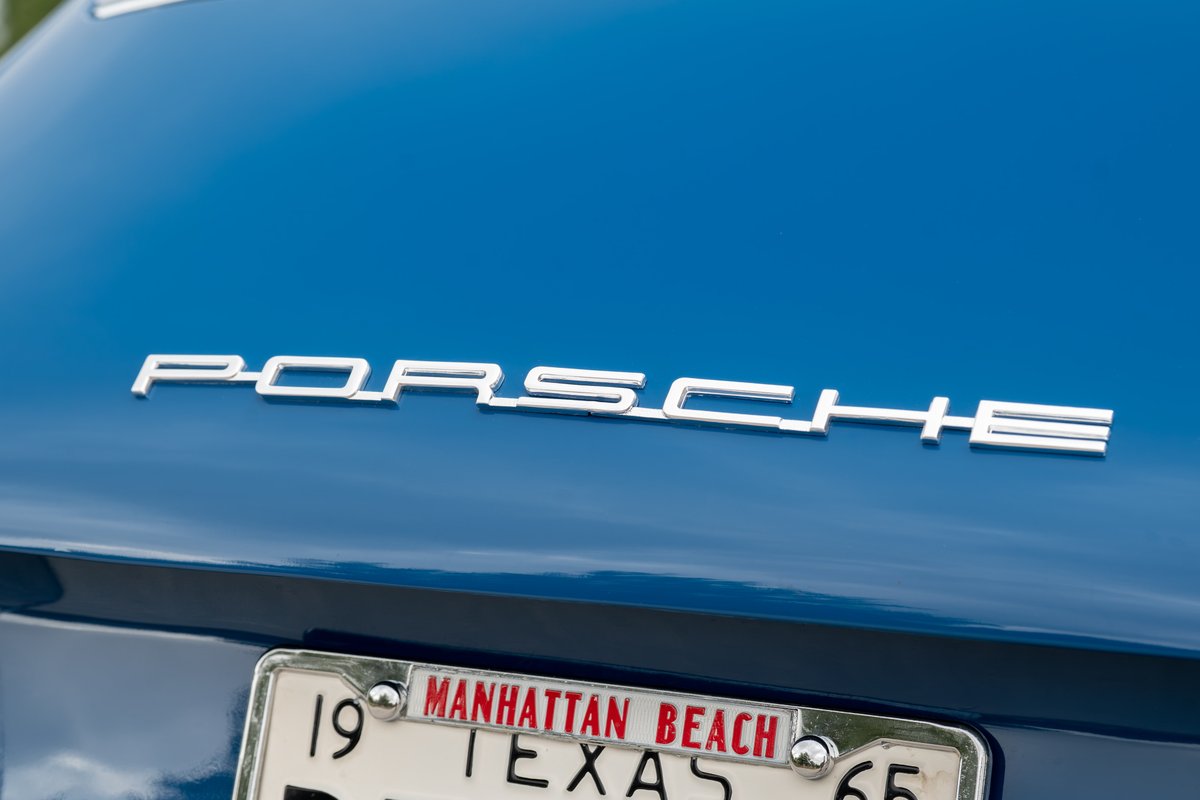 Close-up of the silver "Porsche" badge on the rear of a blue 1965 Porsche 912.
