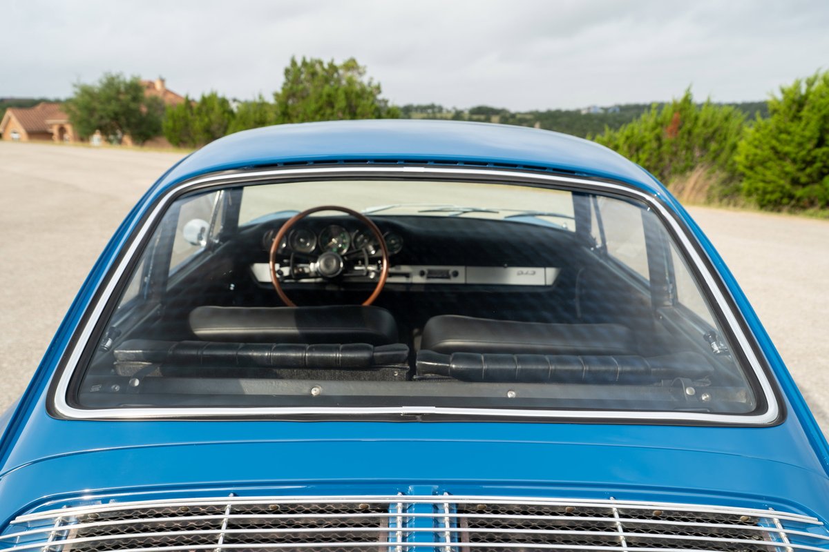 Blue 1965 Porsche 912 interior, rear view. Vintage wooden steering wheel, black seats.