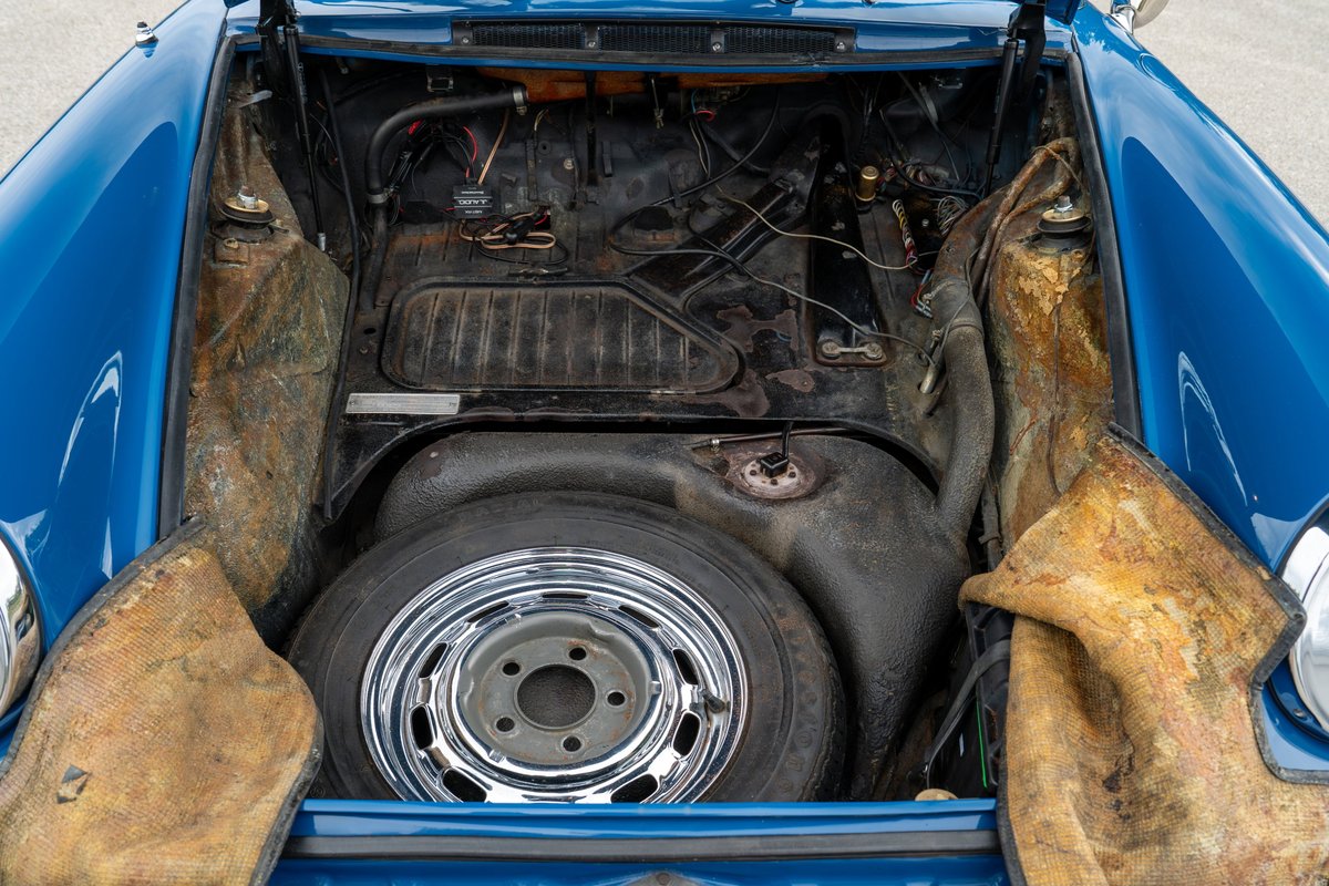 1965 blue Porsche 912 front trunk with spare tire and chrome rim.