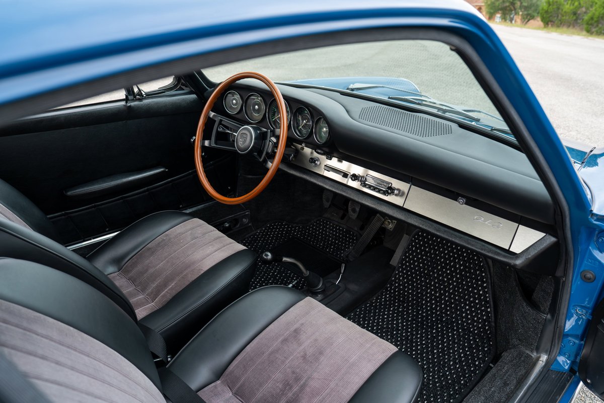 1965 Porsche 912 interior. Blue exterior. Classic wood steering wheel, black and gray seats.