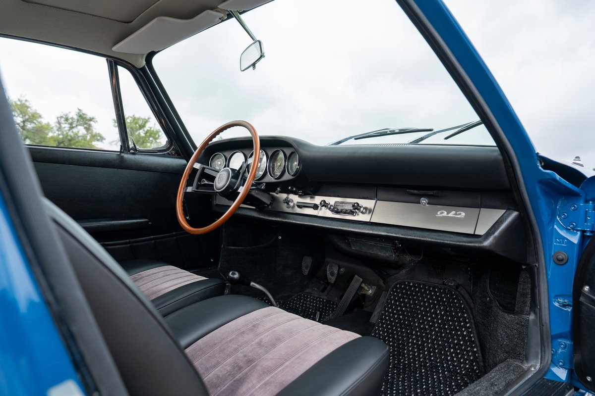 Interior of a blue 1965 Porsche 912, featuring a wood-rimmed steering wheel and 912 badge.