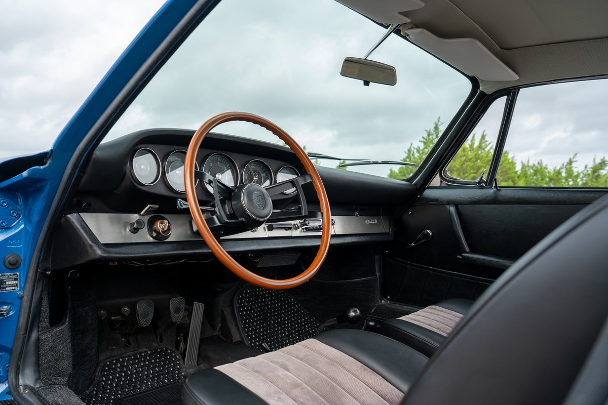 1965 Porsche 912 interior in blue, featuring a wooden steering wheel and tan striped seats.