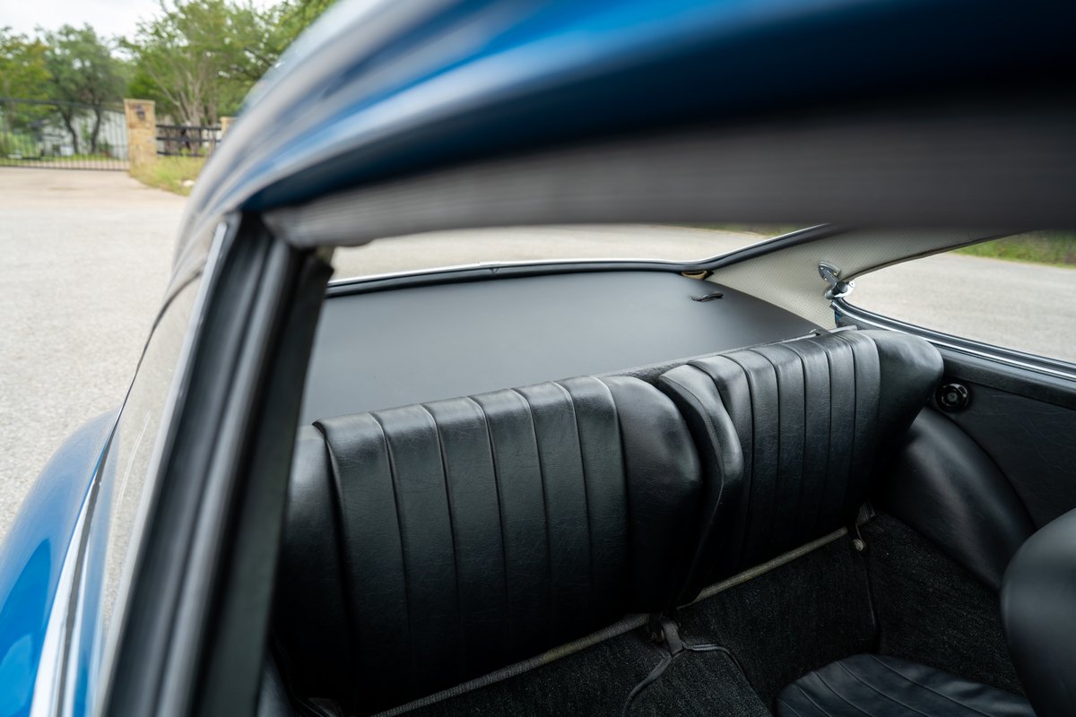 Blue 1965 Porsche 912 rear seats, featuring pleated black upholstery and matching carpet.