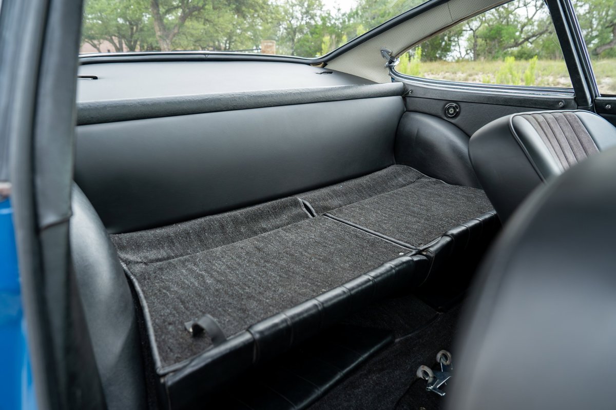Interior of a 1965 blue Porsche 912, showing rear seat with charcoal carpet and black vinyl trim.