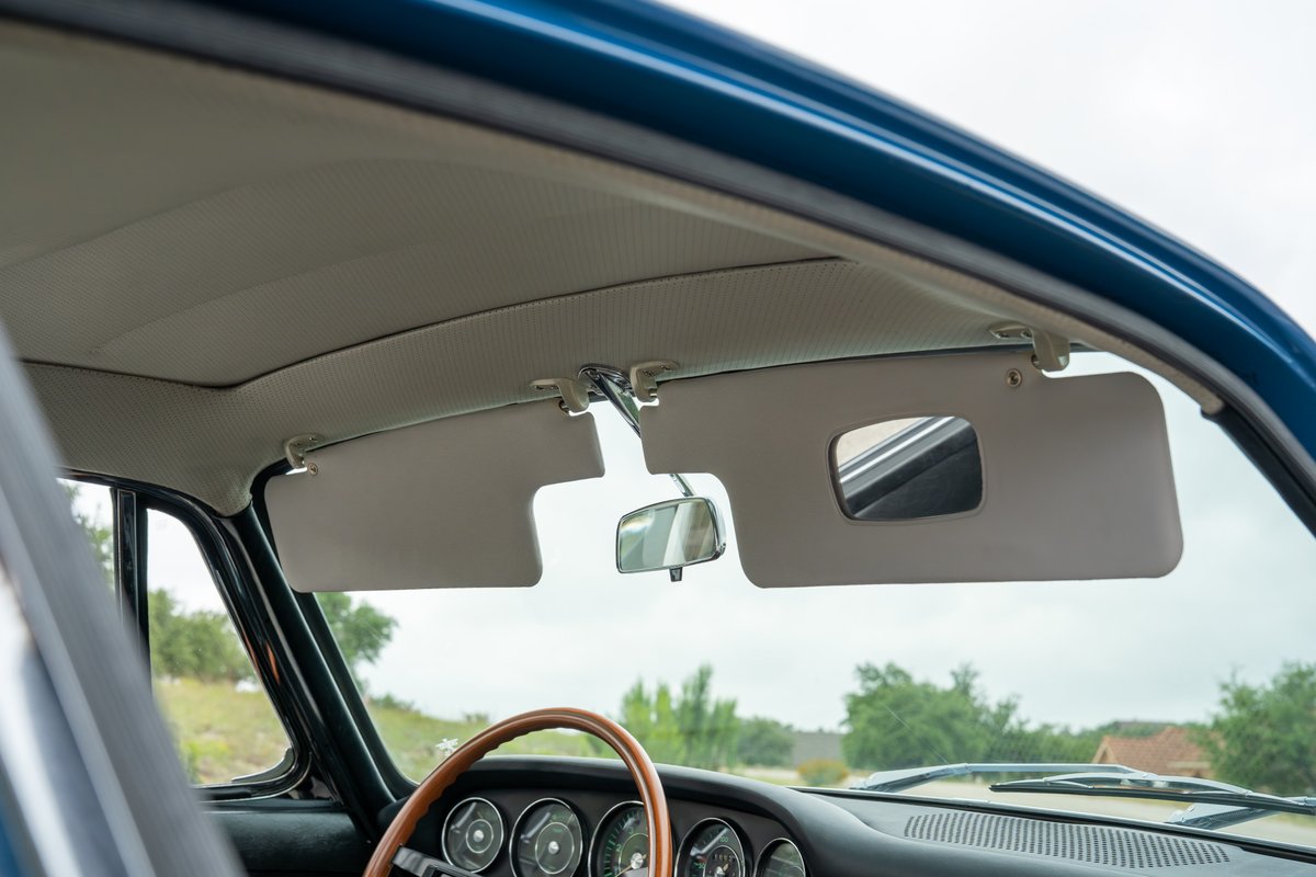 Interior of a blue 1965 Porsche 912, showing sun visors with vanity mirror and rearview mirror.